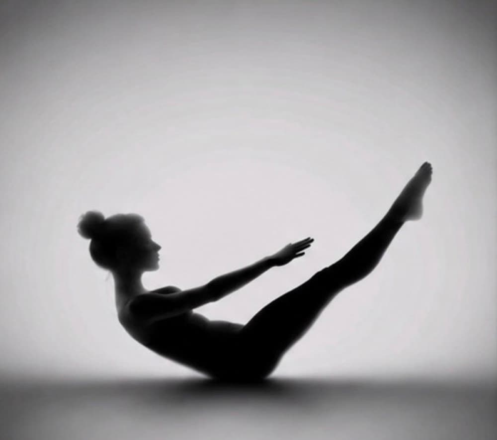 Silhouette of a woman balancing, legs and arms extended