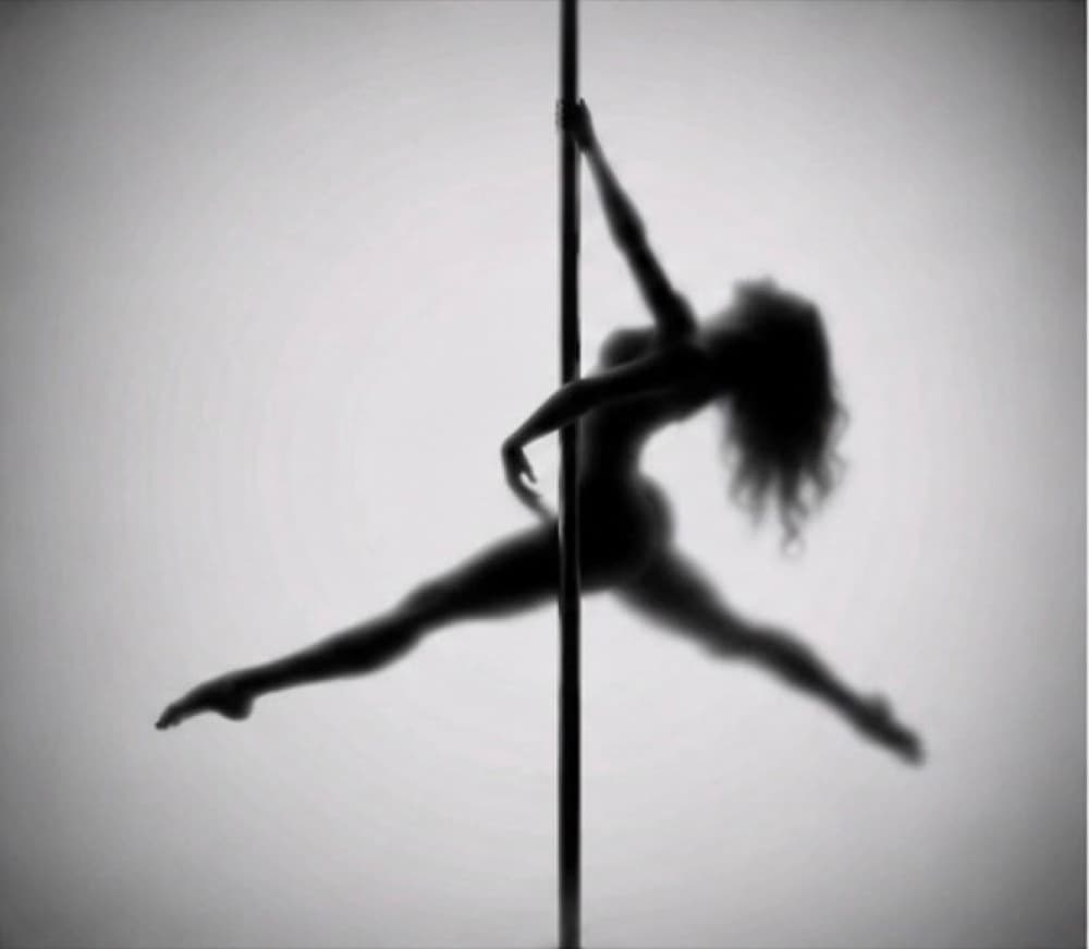 Silhouette of a dancer in the splits, suspended on the pole