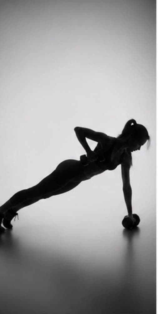 Silhouette of a woman supporting herself on one arm, a dumbbell on the floor